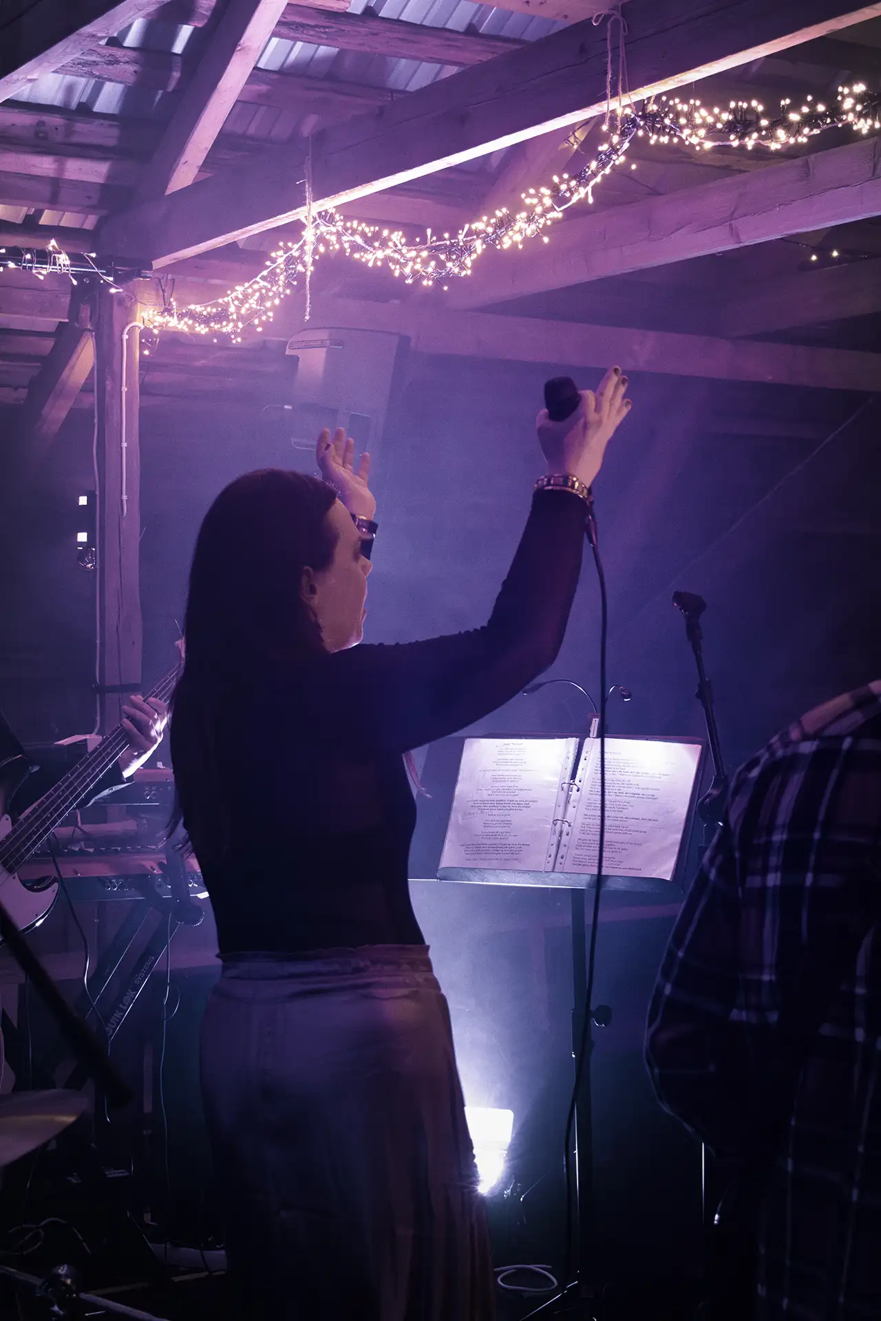 Laulaja esiintymässä lavalla tunnelmallisessa konserttivalaistuksessa.
